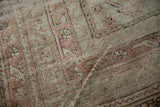 Close-up of hand-knotted vintage Oushak pile, showing faded dusty rose floral motifs.