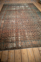 Close-up of antique Hamadan rug: dark teal Samovar border, blush Herati field, rewoven ends.