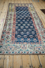 Antique Kurd runner's cobalt blue field with repeating plant motifs, framed by a terracotta border.