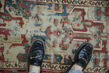Close-up of geometric arabesque pattern showing foundation wear, raspberry red, dusty teal.