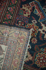 Antique Mahal carpet detail revealing hand-knotted navy, red, green Herati pile and visible woven foundation.