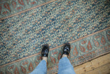 Distressed Malayer runner featuring repeating boteh field and geometric border in blues, terracotta.