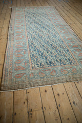 Vintage Malayer rug showing distressed dusty blue boteh field and geometric terracotta border.