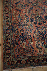 Vintage Sarouk rug's dusty rose field, showing navy, beige, terracotta vased plants.