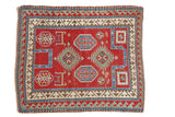 Antique Fachralo Kazak prayer rug with geometric medallions and a wave border in rich gem tones.
