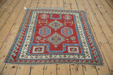 Full perspective of an antique Kazak rug with a geometric, gem-toned prayer design.