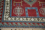 Corner of an antique Kazak rug featuring a wave motif border and stylized geometric figures.