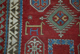 A ram's horn medallion near the reciprocating wave border of an antique collector Kazak rug.