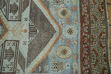 Distressed Malayer runner border with geometric patterns, rust, beige, sky blue, and visible fringe.