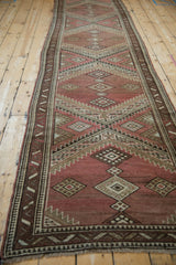 Faded red and brown vintage Caucasian runner showing serrated medallions and pawn border motif.