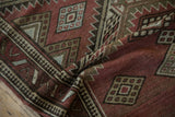 Textural close-up of serrated geometric patterns on Caucasian runner in dusty aubergine, sage.