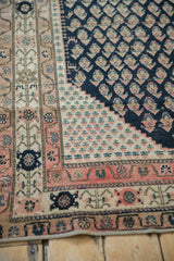 Corner detail of an antique Malayer rug, with navy botehs and a fuchsia patterned border.