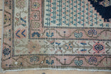 Antique Malayer rug corner, dusty rose border, ivory field, and intact warp macrame edge.