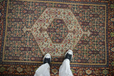 Overhead view of a vintage Senneh rug, highlighting the scale of its hexagonal medallion and Herati pattern.
