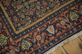 Corner detail of a Senneh rug with a madder red Samovar Turtle border and short ivory fringe.