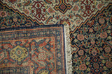 Corner detail of a vintage Senneh rug showing the woven foundation, fringe, and dark blue selvage.