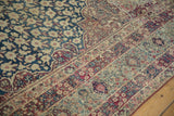 Antique Kermanshah carpet detail: scrolling Islimi border, millefleur blossoms, soft blue and aubergine.