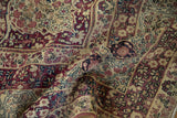 Antique Kermanshah carpet's intricate millefleur, aubergine, ivory, and navy blue scrolling border details.