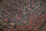 A vintage carpet's madder red border with boteh designs alongside the intricate navy Herati field.