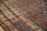 Blue abrashes visible across the boteh and cypress tree border of a vintage Persian carpet.