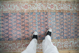Showing the worn texture and staggered boteh pattern of a distressed Malayer rug from a top-down view.