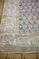 Corner detail of a distressed Persian runner showing the floral border and blue boteh field.