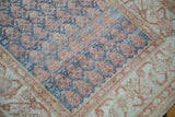 Distressed pile texture of blue botehs beside the sand and copper floral border on a Malayer runner.
