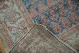 Corner view of a vintage Malayer rug showing its hand-knotted foundation and distressed pile.