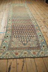 Distressed Malayer rug corner detail with soft teal, terracotta vine border and worn boteh pattern.
