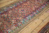 Angled view of an antique Serab runner with allover henna designs and a prominent sky blue border.
