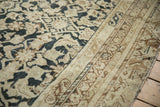 Textured pile of an Antique Distressed Malayer showing charcoal Herati design and beige border.