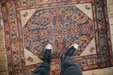 Overhead view showing the scale of a worn antique Hamadan rug with its detailed Herati pattern.