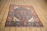 Angled perspective of an antique square Hamadan rug showing the complete geometric Herati design.