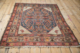 Angled view of an antique Hamadan rug highlighting its worn texture and color abrashes.