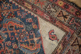 A time-worn ivory corner spandrel of an antique Hamadan rug, featuring a singular boteh motif.