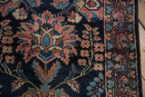 Detailed floral palmette in dusty rose and teal on the hand-knotted navy blue wool of a vintage Lilihan runner.