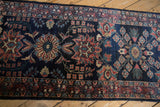 Detailed view of palmette and pomegranate motifs on the glossy navy wool of a Persian runner.