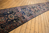 Vintage Lilihan runner seen at an angle, showing its navy field and dusty rose medallions.