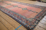 A single column of interconnected diamond medallions runs the length of this antique Hamadan runner.