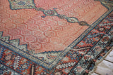 Detail of a dusty red lattice field, stylized medallions, and serrated leaf border on an antique Hamadan runner.