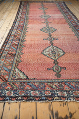 Low angle view of an antique Hamadan runner's intricate border beside its faded lattice field.