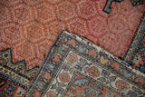 The hand-knotted foundation and worn ruby red pile of an antique Hamadan runner's corner.