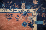 Antique Chinese Peking carpet corner detail: navy border, pale copper field, floral vase motif.