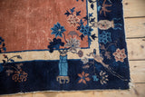 Pale copper field, navy border, blue vase with floral-avian motifs on antique Peking rug.