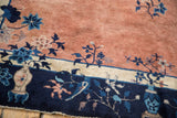 Antique Peking carpet detail: navy blue border with stylized vase and pale copper floral field.