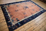 Antique Peking carpet corner, showing its aged navy border with florals and pale copper field.