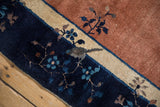 Antique Peking carpet detail: navy border, ivory stripe, pale copper field, floral motifs.