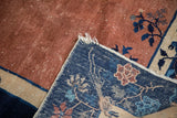 Folded antique Peking carpet corner, showing hand-knotted dark blue foundation and copper pile.