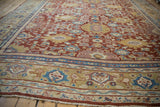 Low angle perspective of the intricate floral border and cherry red field on an antique Mahal carpet.