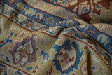 Dense pile texture of a draped antique Mahal carpet with gold, blue, and mauve motifs.